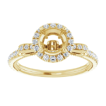 This vintage halo engagement ring setting is designed to hold a 6.5mm round center stone. Featuring intricate scrollwork details and a pave diamond band, this elegant mounting is available in 18K gold. Ideal for custom engagement jewelry.