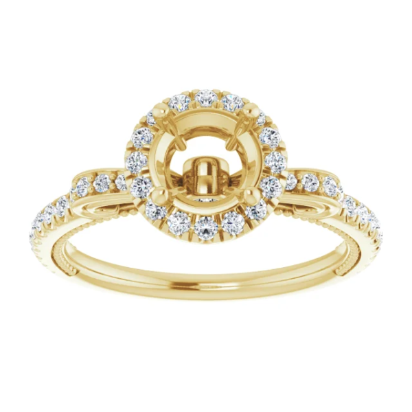 This vintage halo engagement ring setting is designed to hold a 6.5mm round center stone. Featuring intricate scrollwork details and a pave diamond band, this elegant mounting is available in 18K gold. Ideal for custom engagement jewelry.