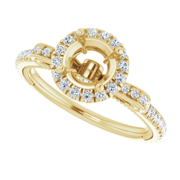 This vintage halo engagement ring setting is designed to hold a 6.5mm round center stone. Featuring intricate scrollwork details and a pave diamond band, this elegant mounting is available in 18K gold. Ideal for custom engagement jewelry.