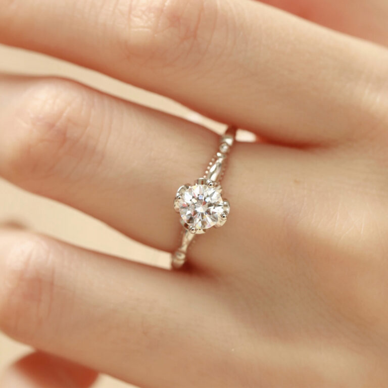 This engagement ring showcases a 6.0mm main stone set in a graceful flower-inspired design. In addition, you can select moissanite, lab diamond, or a colored gemstone as the center, and choose yellow, white, or rose gold for the band. Whether you prefer a timeless classic or a fresh modern twist, you shape the final look. Furthermore, you can explore our Custom Rings Page or pair it with styles from our Wedding Bands Collection .