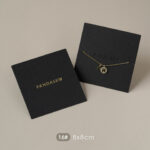 This custom black jewelry card features a rigid paperboard structure and precise cut-outs. It provides a professional display solution for jewelry.