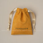 This custom faux sheepskin pouch features a soft suede texture and a vibrant finish. It provides an elegant storage solution for jewelry branding.