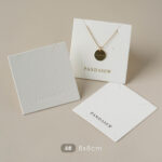 This custom white jewelry card features a soft cotton-textured structure and precise cut-outs. It provides a professional display solution for jewelry.