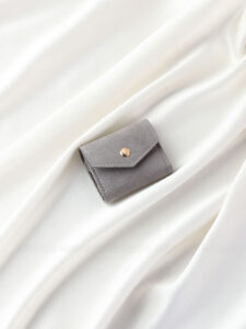 This custom folding jewelry pouch features a snap button and organized interior. It provides an elegant storage solution for jewelry branding.