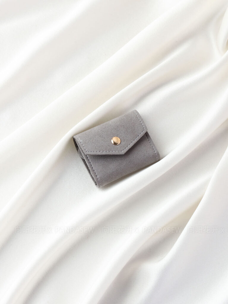 This custom folding jewelry pouch features a snap button and organized interior. It provides an elegant storage solution for jewelry branding.
