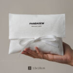 This custom white cotton pouch features a clean design and a soft drawstring closure. It provides an organic storage solution for jewelry branding.