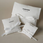 This custom white cotton pouch features a clean design and a soft drawstring closure. It provides an organic storage solution for jewelry branding.