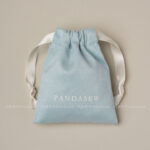 This custom faux sheepskin pouch features a soft suede texture and a vibrant finish. It provides an elegant storage solution for jewelry branding.