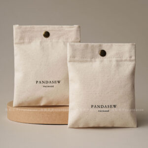 The design features a classic rectangular silhouette. It includes a reinforced snap button closure. Therefore, the jewelry stays in place without any risk of slipping out. The cotton canvas material is selected for its breathability. Additionally, the soft inner surface helps prevent scratches on delicate metal finishes. Its compact size makes it an ideal companion for travel. Moreover, it maintains a professional appearance that aligns with modern branding standards. The tactile experience of the canvas adds a layer of quality to your presentation.