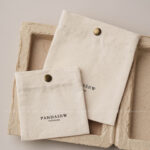 The design features a classic rectangular silhouette. It includes a reinforced snap button closure. Therefore, the jewelry stays in place without any risk of slipping out. The cotton canvas material is selected for its breathability. Additionally, the soft inner surface helps prevent scratches on delicate metal finishes. Its compact size makes it an ideal companion for travel. Moreover, it maintains a professional appearance that aligns with modern branding standards. The tactile experience of the canvas adds a layer of quality to your presentation.