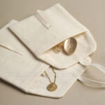 This custom cotton envelope pouch features a unique string tie and soft fabric. It provides a natural and secure solution for jewelry branding.