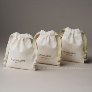 The pouch features a soft yet structured format that keeps jewelry protected during storage and transport. Its natural texture enhances visual warmth without overwhelming the overall presentation. The design remains understated, allowing the jewelry itself to remain the center of attention. This format is suitable for both daily retail use and e-commerce shipping environments.