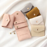 This custom folding jewelry pouch features a snap button and organized interior. It provides an elegant storage solution for jewelry branding.