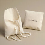 This custom cotton envelope pouch features a unique string tie and soft fabric. It provides a natural and secure solution for jewelry branding.